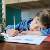 Kind schreibt an einem Tisch. Grafomotorik Kinder in der Ergotherapie